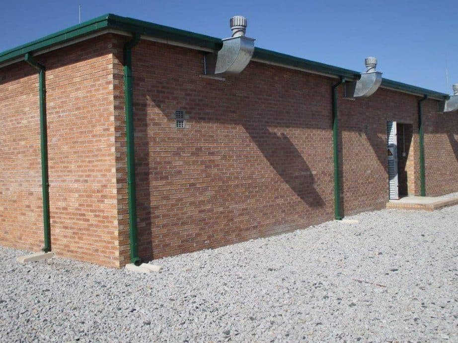 A face-brick substation control building on a stoned yard